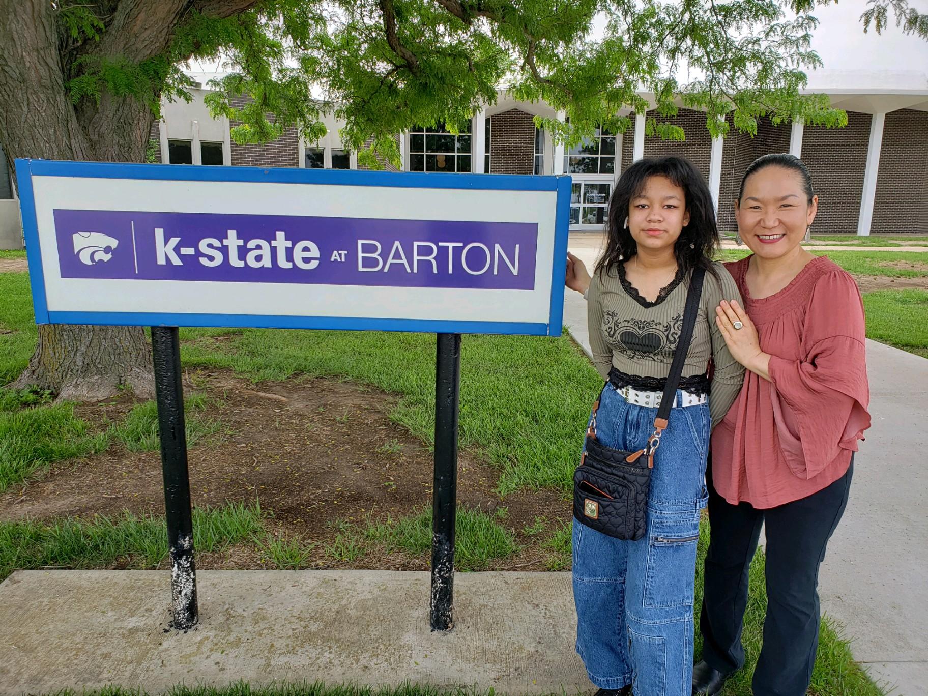 two women stand with the sign on college campus