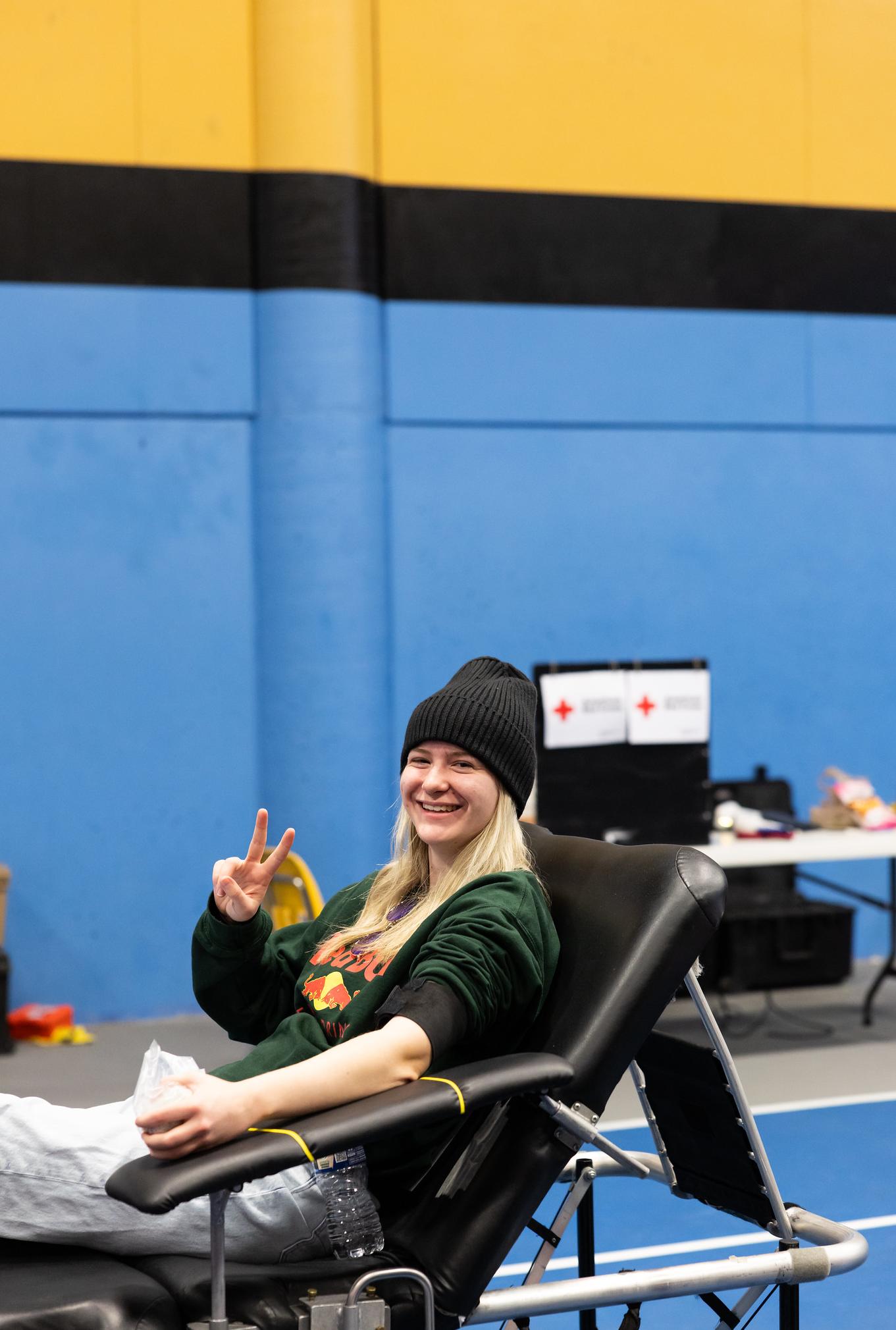 a woman donating blood and giving a peace sign