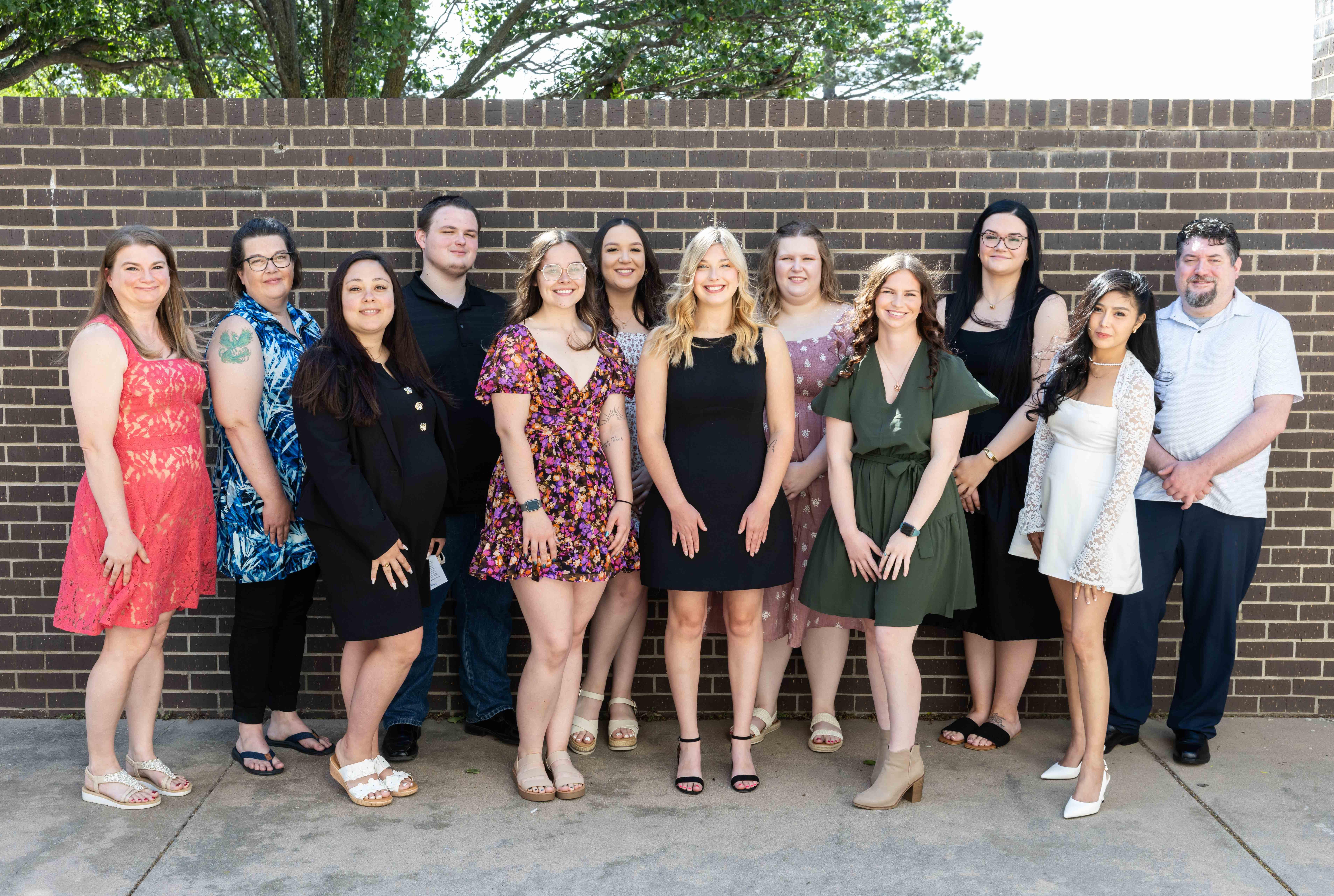 people standing in front of a brick wall dressed nicely