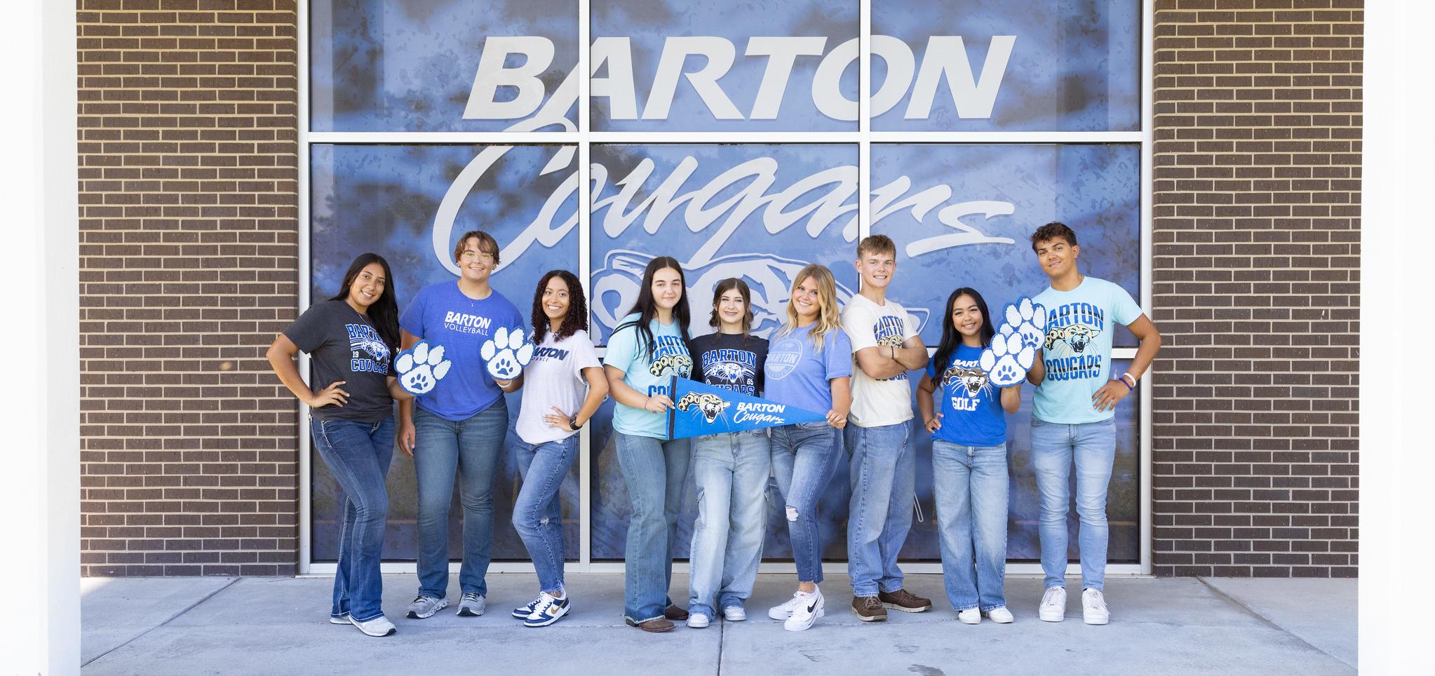 Student ambassadors smile in front of Barton Cougars window