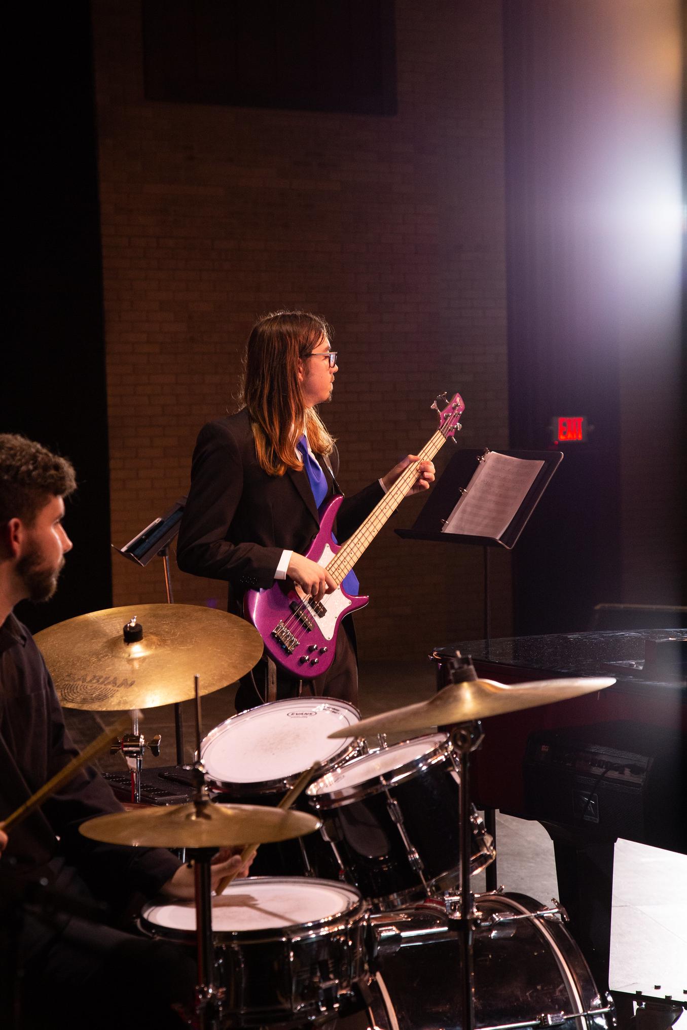 Musician playing bass guitar and drummer drumming