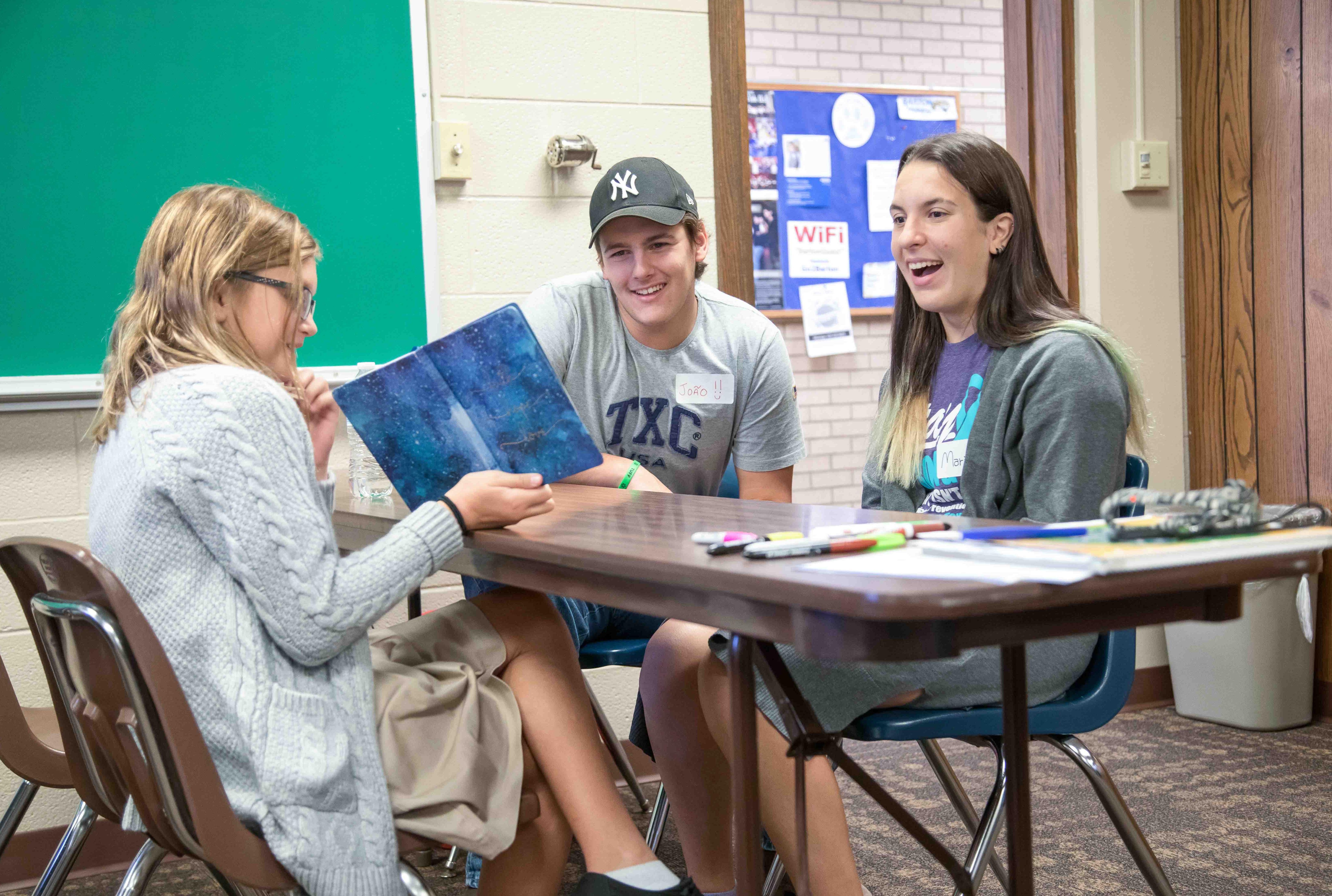 a young student visits with two international students in a classroom