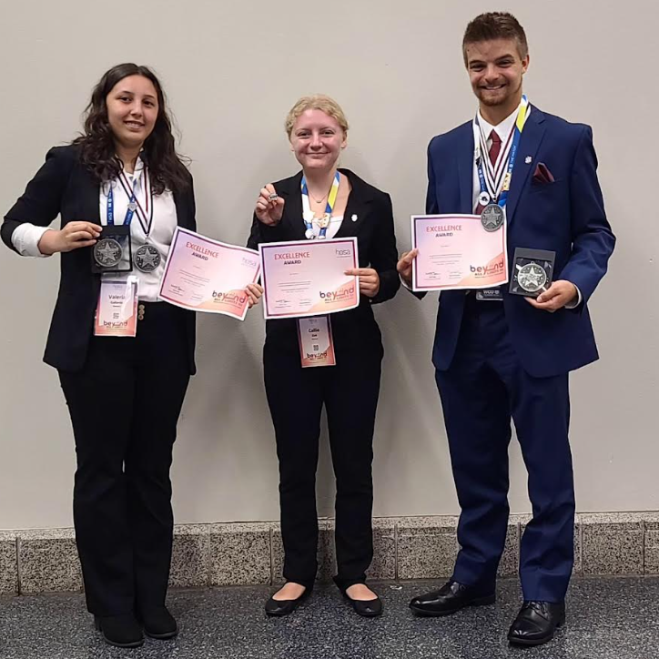 three students with medals and certificates