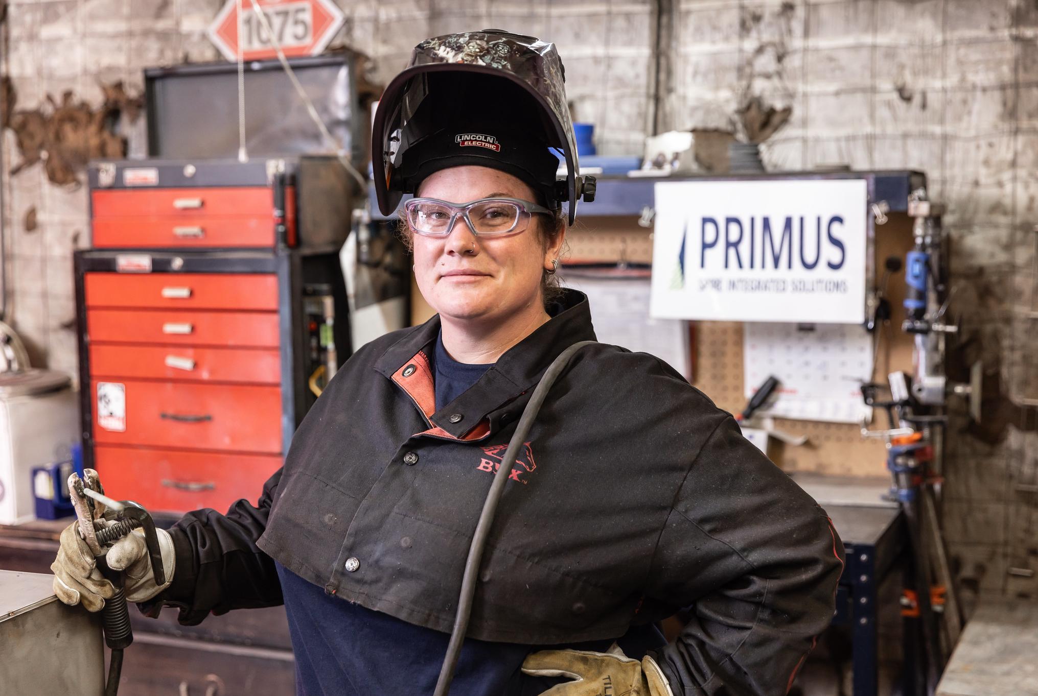 woman welder holding equipment with her protective helmet flipped up