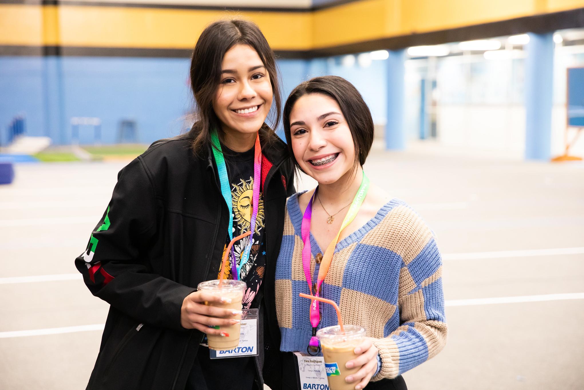 two female event attendees smile while holding their coffee