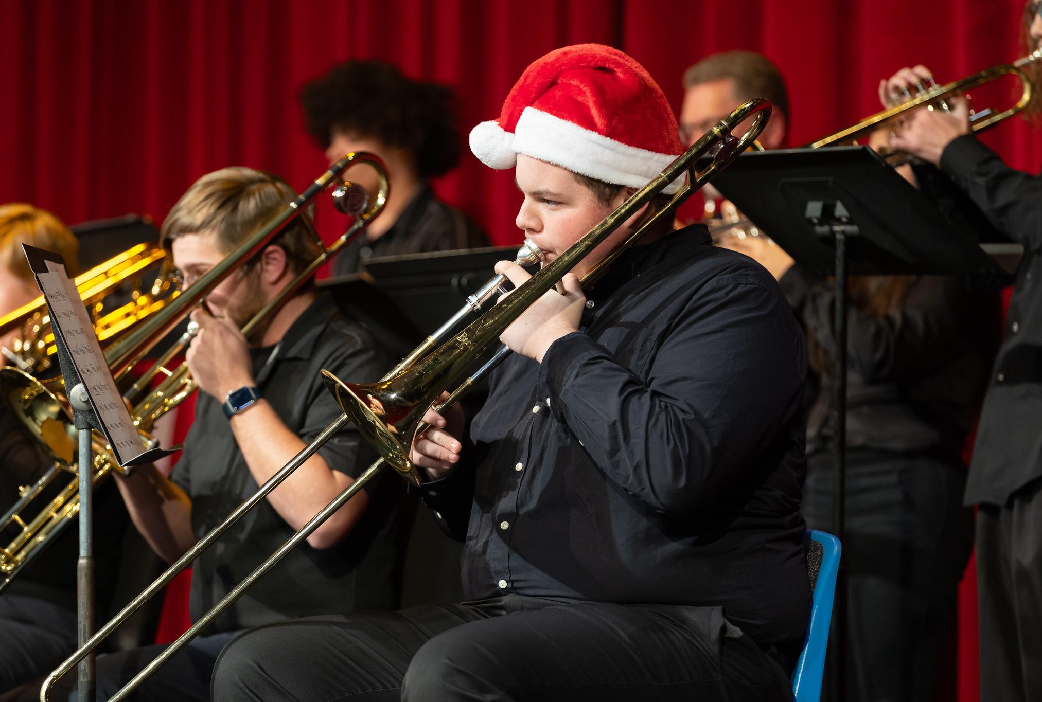 male student playing tuba with santa hat on
