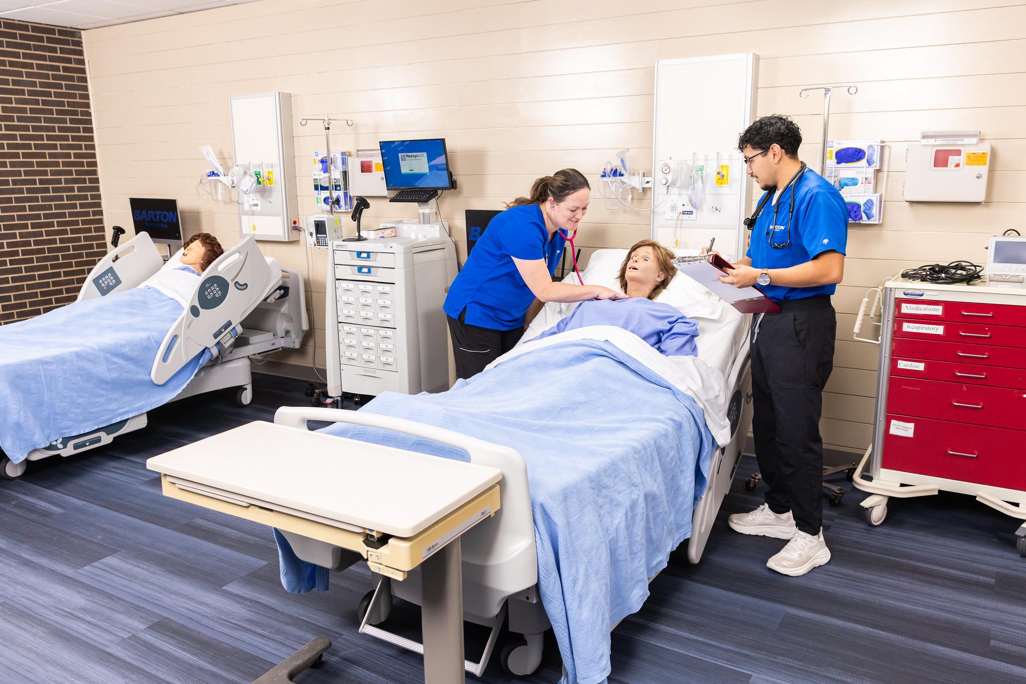 two nursing students in scrubs working on a mannequin