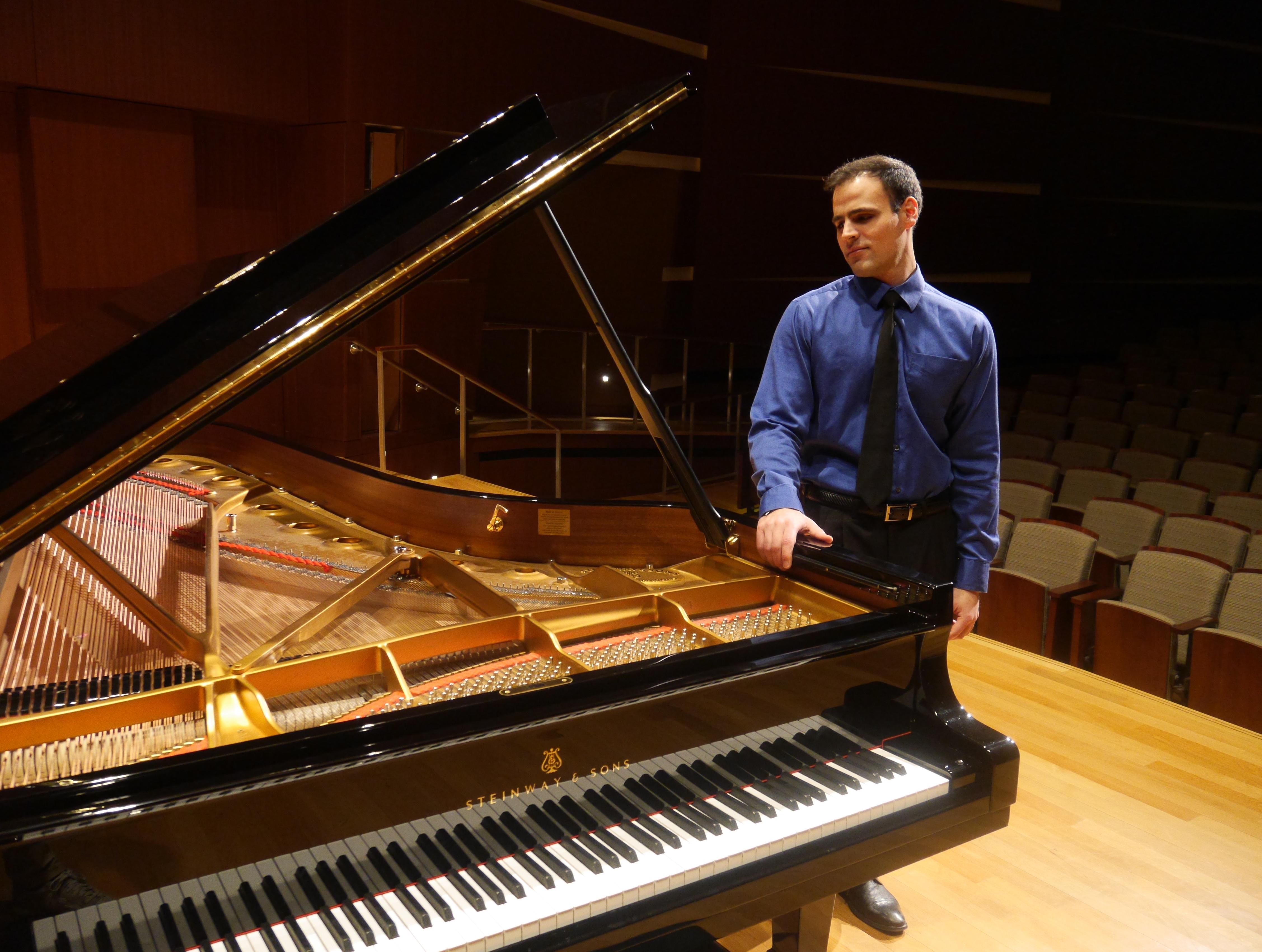 a man standing by a grand piano