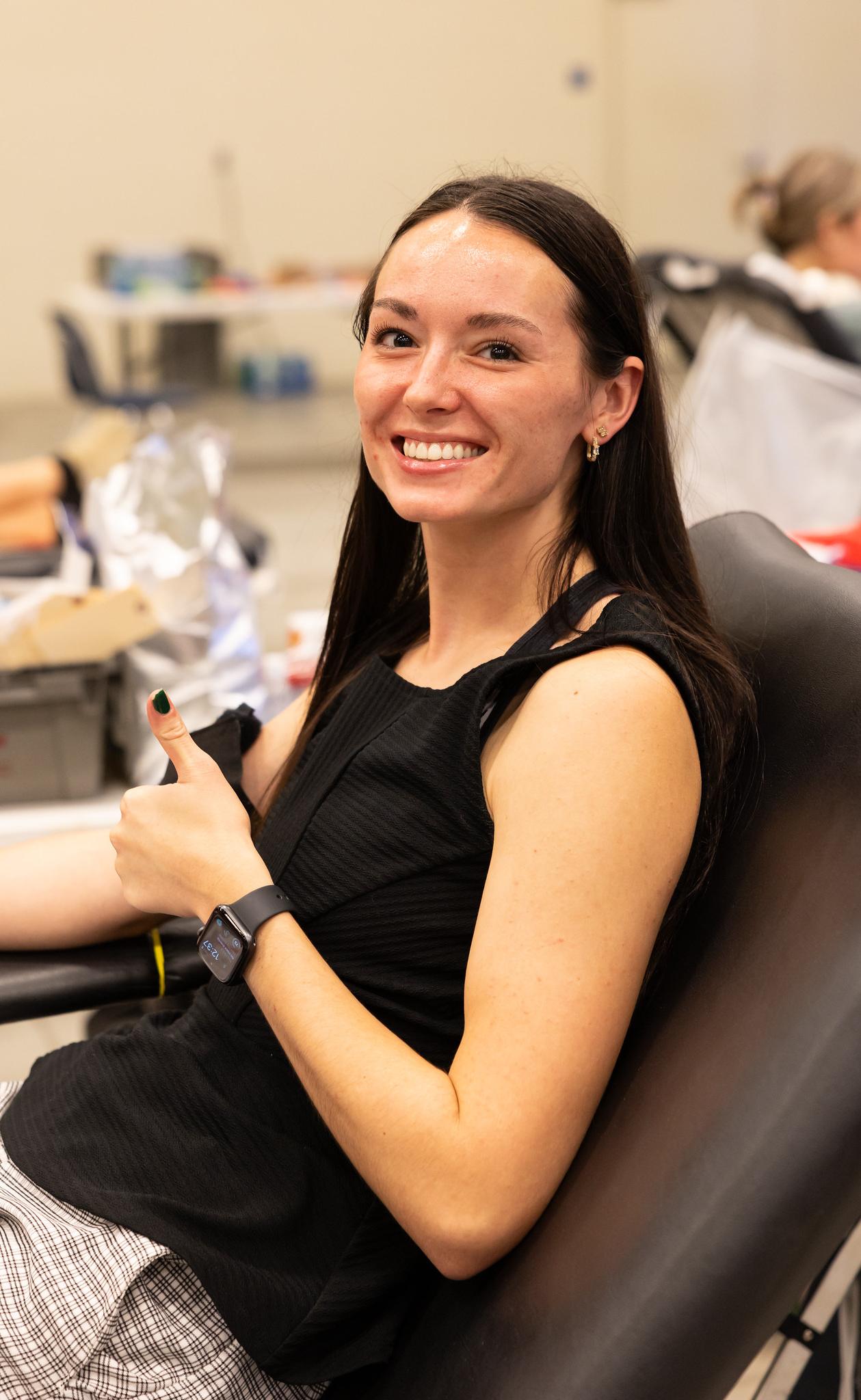 woman donating blood smiling with thumbs up