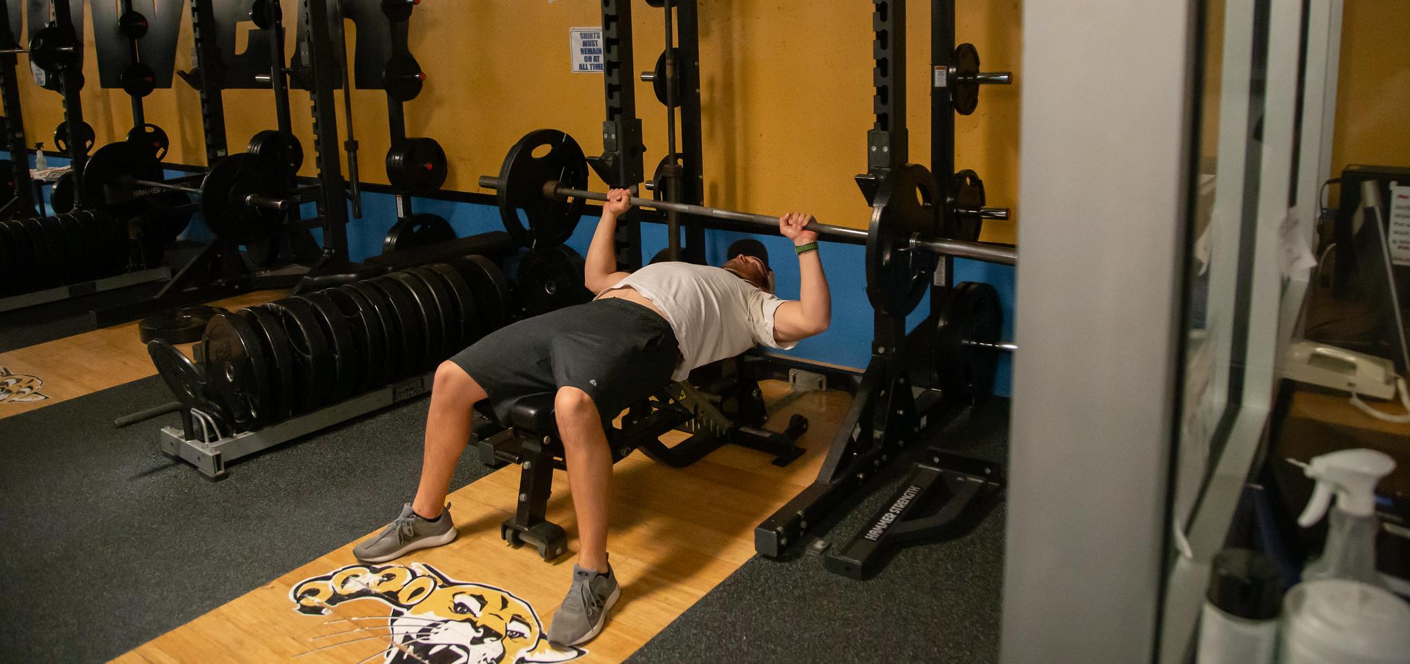 Student lifts weights in the workout room